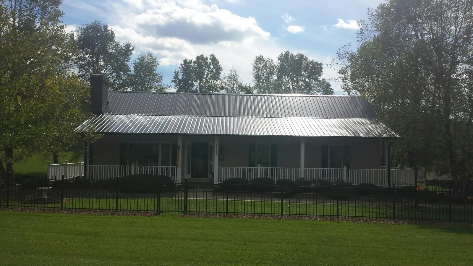 Gray metal roof on a brick ranch with a full width front porch — Gutter Guard Installation work by our crew in Zirconia