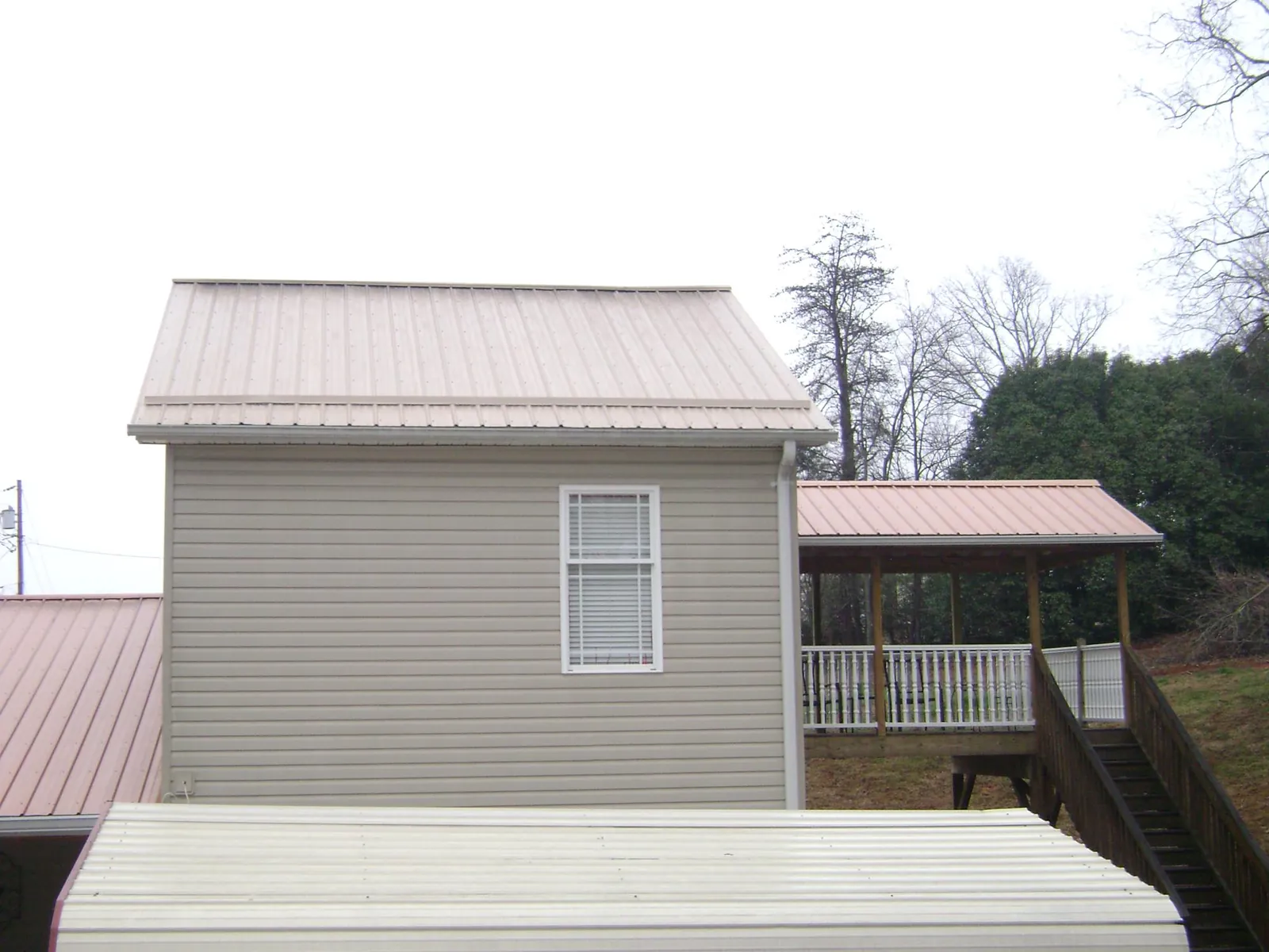 Tan metal roofs on a two story addition and attached porch, from a Roof Replacement job in Zirconia