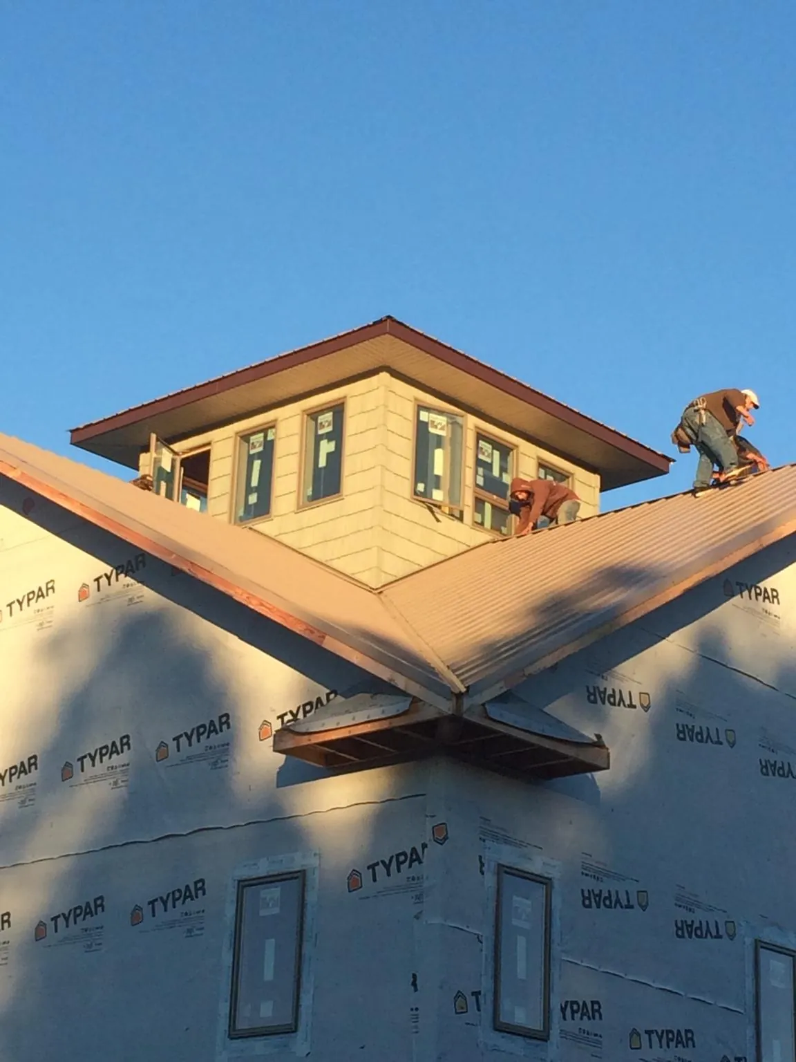 Roofers working around a rooftop cupola on a new metal roof at sunset — Roof Waterproofing in Zirconia by Roofing Brothers